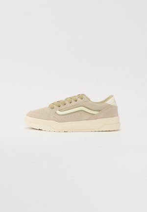 Baskets basses en cuir suédé beige avec bande latérale ondulée crème, lacets beige assortis et semelle en caoutchouc blanc cassé.