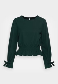 Mörkgrön långärmad topp med en samlad midja, volangkant och knutna manschetter. Tillverkad av ett mjukt och slätt tyg.