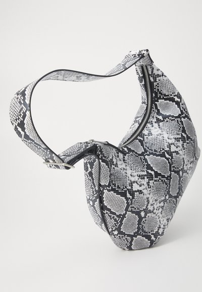 Sac hobo en faux cuir serpent noir et blanc, présentant une silhouette courbée, une sangle ajustable et une fermeture zippée en haut.