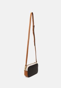 Borsa a tracolla in pelle nera texturizzata con parte superiore crema e dettagli color tan. Dotata di zip dorata e tracolla regolabile. Forma rettangolare compatta.
