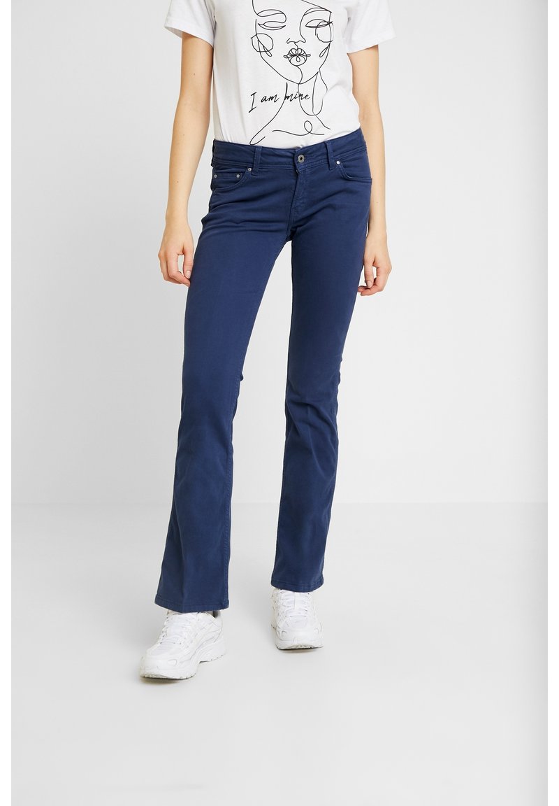 Pantalons extensibles bleu marine avec une coupe fine, dotés d'une fermeture à bouton et éclair, de quincaillerie argentée et de poches avant. Portés avec un t-shirt graphique blanc.