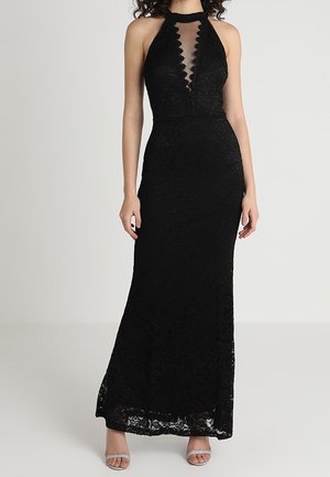 Černé krajkové šaty s halter výstřihem, průhledným límečkem, vroubkovanými okraji, přiléhavým střihem a dlouhou sukní sahající až ke kotníkům. Stříbrné sandály na podpatku.