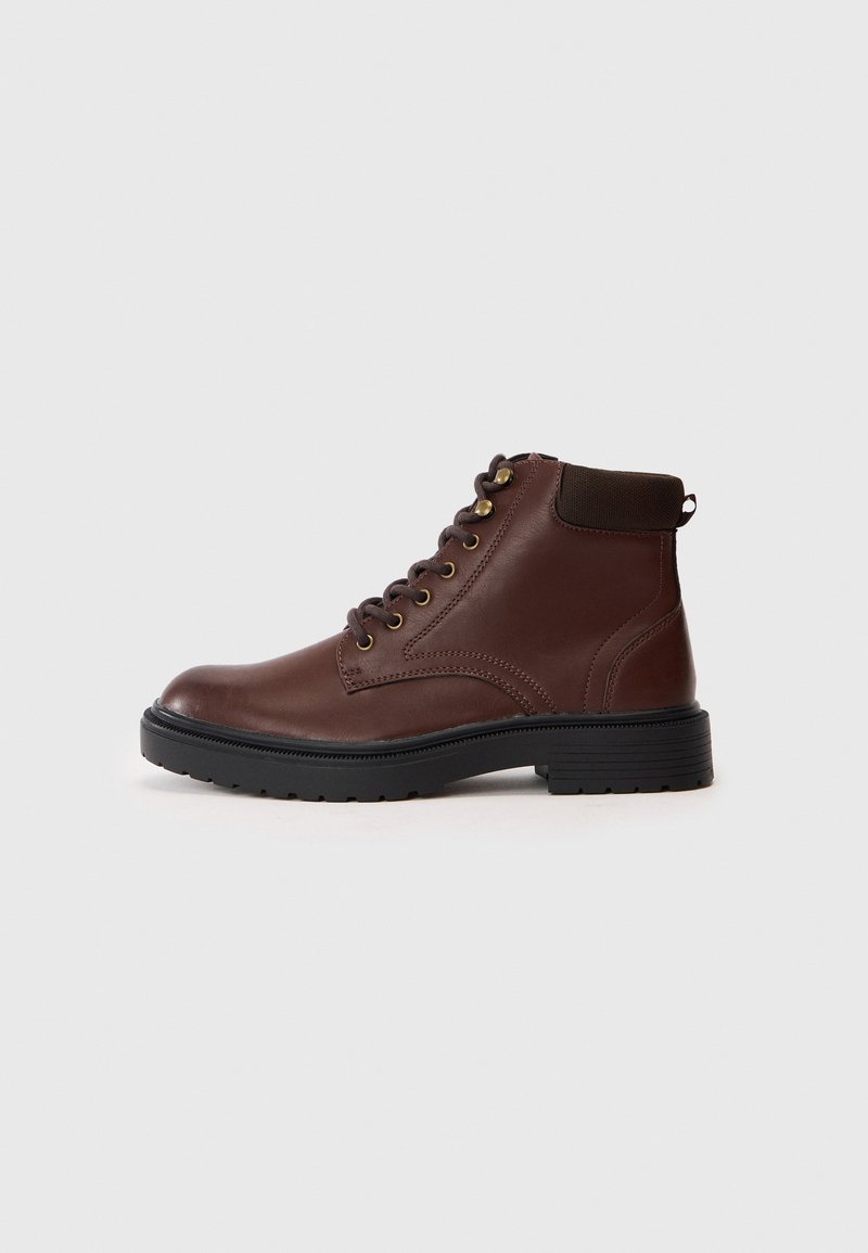 Bottines en cuir marron avec un laçage sur le devant, bout rond, semelle en caoutchouc et col rembourré. Dotées d'œillets dorés et d'un talon texturé.