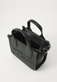 Sac à main en cuir noir texturé avec des poignées courtes, un compartiment zippé et un détail de logo embossé sur le devant. Forme compacte rectangulaire.