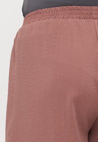 Løse bukser i et blødt mauve-stof, med en elastisk talje og subtil tekstur, side lommer og en afslappet silhuet.