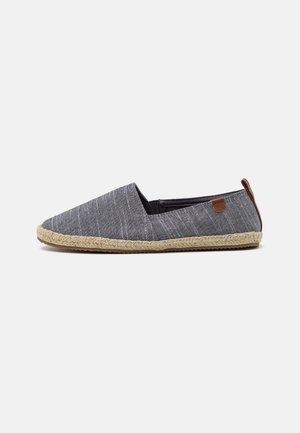 Grijze slip-on espadrille schoen met gevlochten juten zool en bruin leren trekkoord, weergegeven op een witte achtergrond.