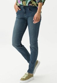 Mörkblå denim skinny jeans med fem fickor, midja i normal höjd och enkel sömnad. Kommer tillsammans med gröna och vita snörskor.