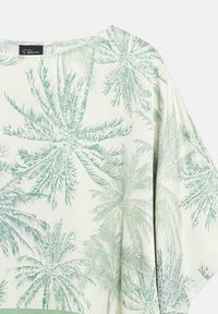 White long-sleeve shirt with light green palm tree print and round neckline, featuring an S.Oliver brand label inside the collar.