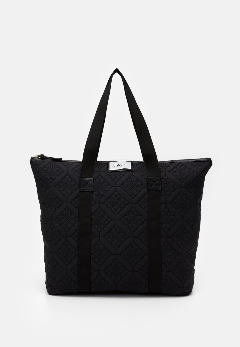 Sort quiltet tote taske med diagonal diamantmønster, to sorte stofhåndtag og en lukning med toplynlås. Har en label foran.