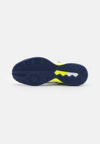 Weiße und marineblaue Sohle eines sportschuhs mit strukturiertem Gummimuster; verfügt über leuchtend gelbe Akzente und kreisförmiges Griffdetail.