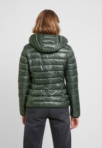 Polstret grøn jakke med en skinnende overflade, hætte og vertikalt quiltet design. Har elastiske manchetter og en tætsiddende silhuet.