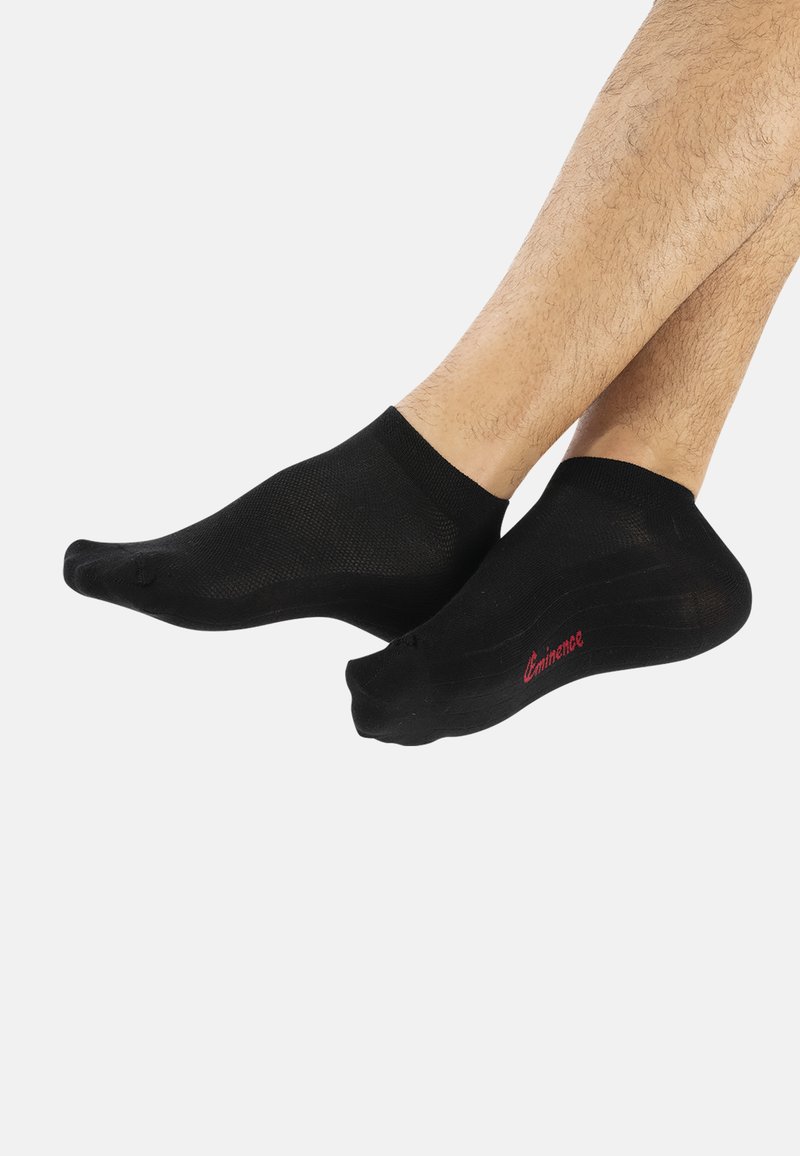 Chaussettes noires de cheville en tissu doux et extensible. Elles présentent un logo rouge sur le côté et un bout sans couture pour le confort.