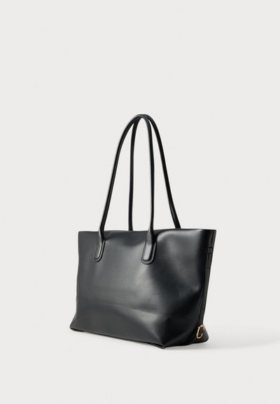 Sac cabas en cuir noir avec doubles longues bandoulières et un petit anneau doré sur un côté, présenté sur fond uni.