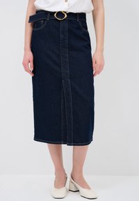 Falda midi de mezclilla oscura con una abertura frontal, hebilla circular dorada, diseño de cinco bolsillos y detalles de costura en contraste.
