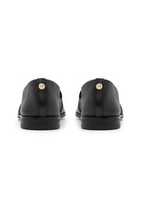 Chaussures en cuir noir avec une texture lisse et une forme arrondie, dotées d'un petit accent en métal au dos et d'un talon bas.