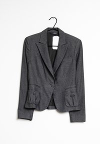 Harmaa blazer, joka on valmistettu teksturoidusta kankaasta, sisältää muotoillun suunnittelun, kaksi nappia suljettavaksi sekä etutaskut pyöreillä yksityiskohdilla.