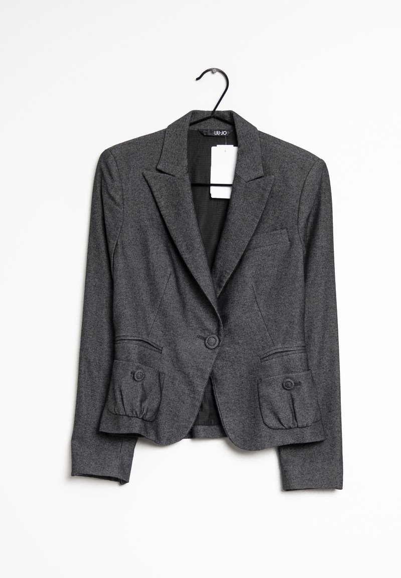 Harmaa blazer, joka on valmistettu teksturoidusta kankaasta, sisältää muotoillun suunnittelun, kaksi nappia suljettavaksi sekä etutaskut pyöreillä yksityiskohdilla.