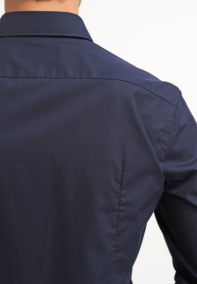Chemise bleu marine à boutons en tissu soyeux, dotée d'un col classique et de détails de couture discrets le long du dos et des coutures des épaules.