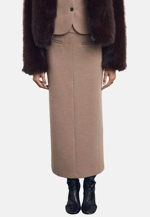 Falda larga de mezcla de lana marrón con una silueta recta, combinada con una chaqueta ajustada de piel sintética marrón oscuro, que acentúa la textura de la tela.