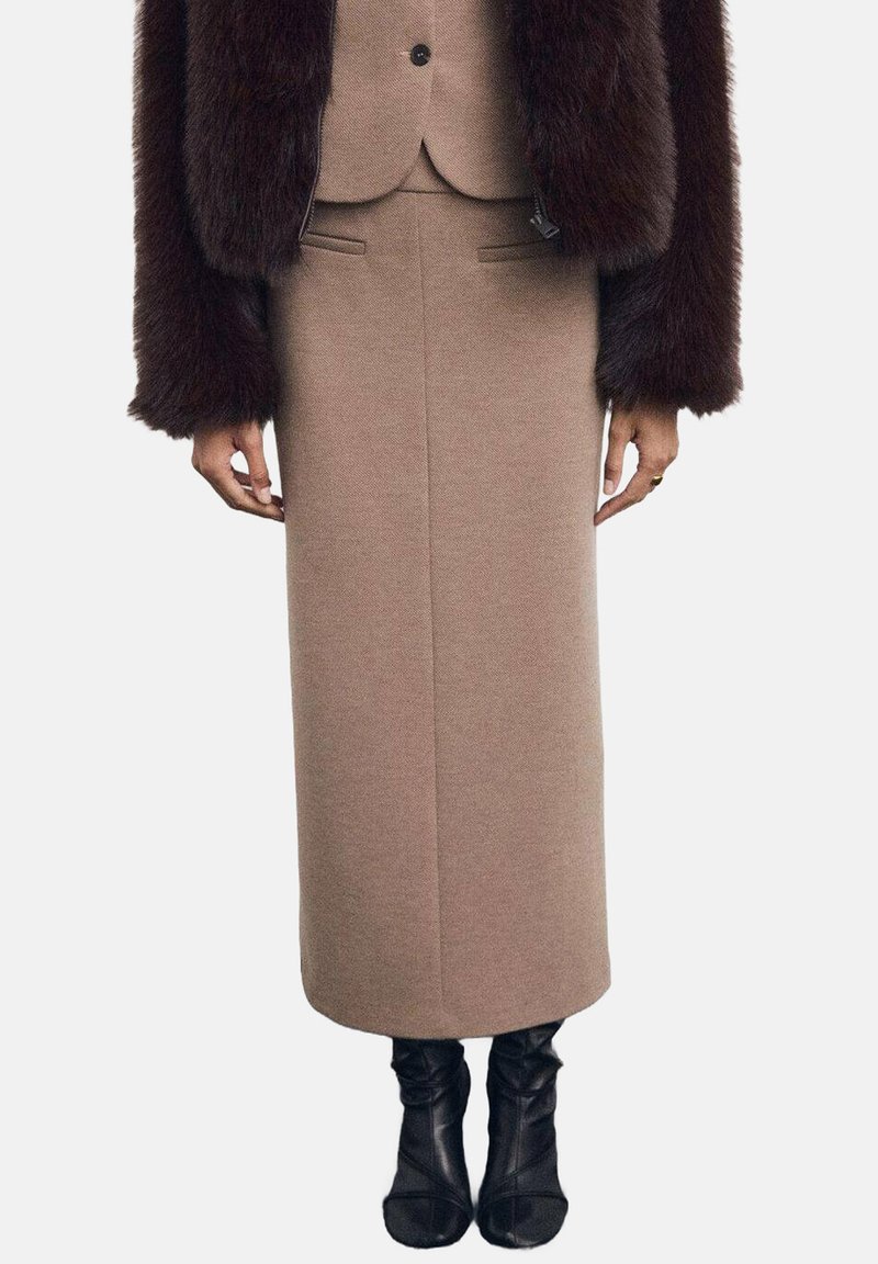 Falda larga de mezcla de lana marrón con una silueta recta, combinada con una chaqueta ajustada de piel sintética marrón oscuro, que acentúa la textura de la tela.