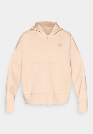 Beige lynlåshoodie lavet af blødt materiale, med hætte, to forlommer og diskret logodetalje på brystet.