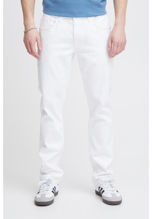 Vaqueros de mezclilla blancos con corte recto, cinco bolsillos y un ligero estiramiento, combinados con zapatillas gris y negras y una camiseta azul.