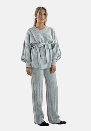 Completo grigio in maglia composto da un maglione e pantaloni con strisce verticali, maniche a palloncino, cintura da annodare e texture morbida, abbinato a calzature nere.