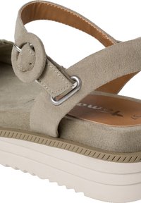 Beige Wildledersandale mit einer runden Metallbuckle, gepolstertem Fußbett und einer hellen, dicken Plattformsohle mit strukturierten Rillen.