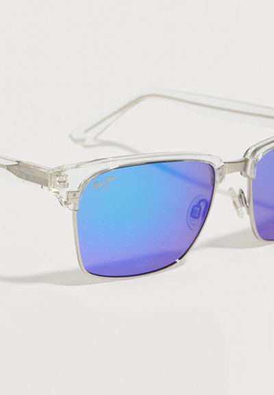 Διάφανα τετράγωνα γυαλιά ηλίου με διαφανή σκελετό και μπλε καθρεφτιστικούς φακούς, με ένα μικρό λογότυπο στην επάνω γωνία του αριστερού φακού.