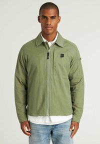 Groene, zip-up jas met kraag, twee voorzakken en een klein logo op de borst. Beschikt over lange mouwen en een soepele textuur.