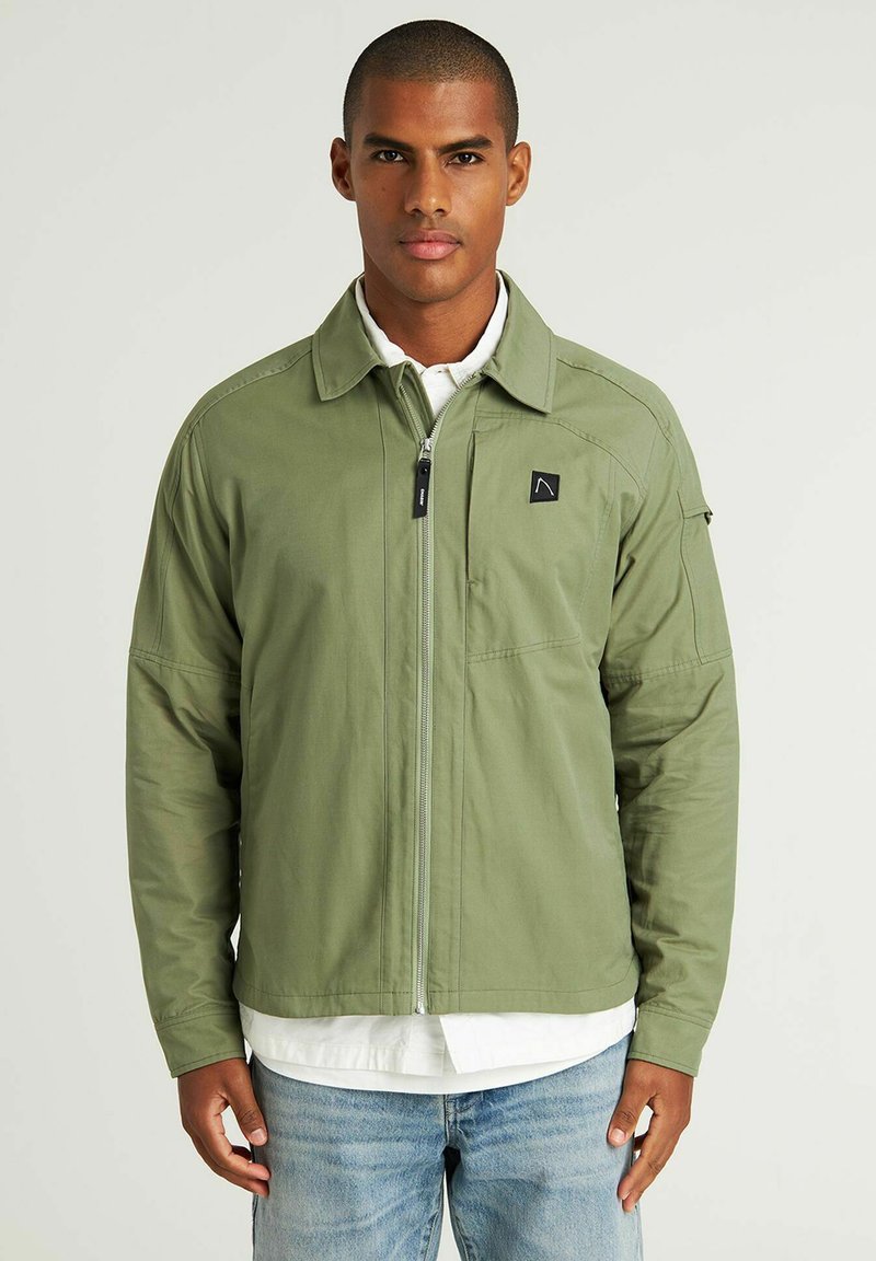 Groene, zip-up jas met kraag, twee voorzakken en een klein logo op de borst. Beschikt over lange mouwen en een soepele textuur.