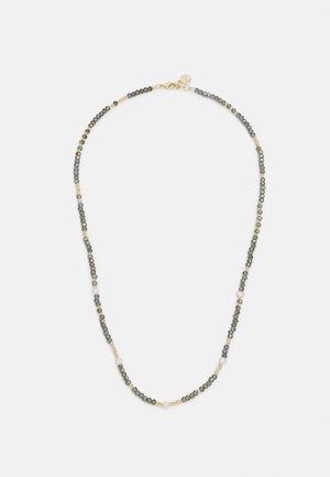 Collier délicat avec de petites perles gris foncé et or, accentué par des perles blanches espacées régulièrement et un fermoir doré avec une étiquette ronde.