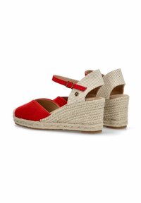 Sandalias de cuña de tela roja con correa en el tobillo, tacón texturizado en beige y elementos de yute trenzado. Diseño de punta redondeada con un acabado ligeramente brillante.