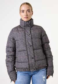 Veste rembourrée avec un col montant en motif chevrons, couleurs gris et marine, dotée de boutons pressions et de poignets élastiques.