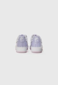 Fialové lakované kožené tenisky Nike s bielymi akcentami, ktoré majú zaoblený dizajn, textúrovanú podrážku a logo "AIR" na päte.