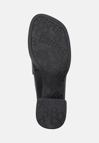 Black shoe sole with "CAMPER" text, floral patterns, and the number 38 embossed on the heel area.