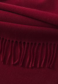 Burgundy wool scarf with soft texture, featuring fringed edges and a smooth finish. Folds create depth in the fabric.
