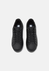 Un paio di sneaker nere basse con lacci e targhette con il marchio sulla linguetta, viste dall'alto su uno sfondo bianco.