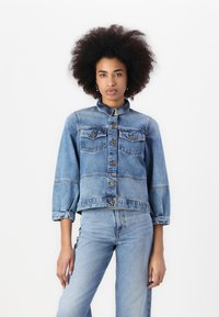 Blue denim jacket with a cropped design, button-up front, two chest pockets, and rolled-up sleeves. Soft texture and classic styling.