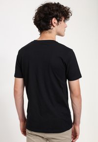 Černé tričko s krátkým rukávem z hladké bavlny, s klasickým kulatým výstřihem a jednoduchým, nenápadným designem.