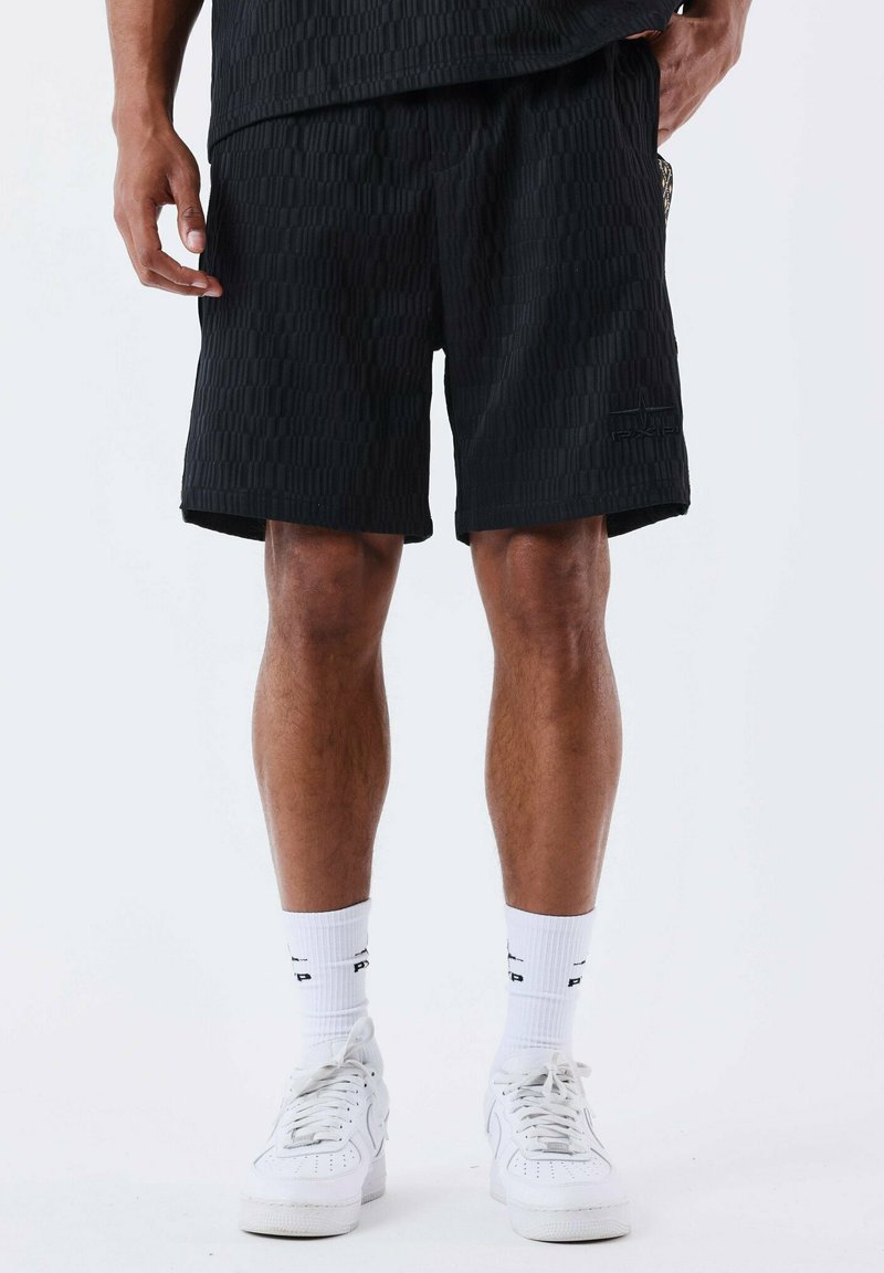 Black shorts with a textured pattern, elastic waistband, side pockets, and a small logo; worn with white socks and sneakers.