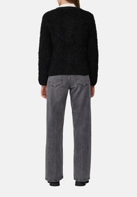 Schwarzer, fuzzie strukturierter Pullover und hochtaillierte graue Jeans aus Denim mit geradem Bein, ausgestattet mit Gesäßtaschen und minimalen Nähdetails.