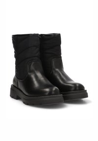 Botas de tobillo negras con una parte inferior de cuero brillante y una parte superior de tela acolchada. Suelas de goma gruesas y cierre lateral para facilitar su uso.
