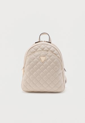 Sac à dos matelassé beige avec poche zippée à l'avant, logo triangulaire doré et poignée supérieure sur fond blanc uni.