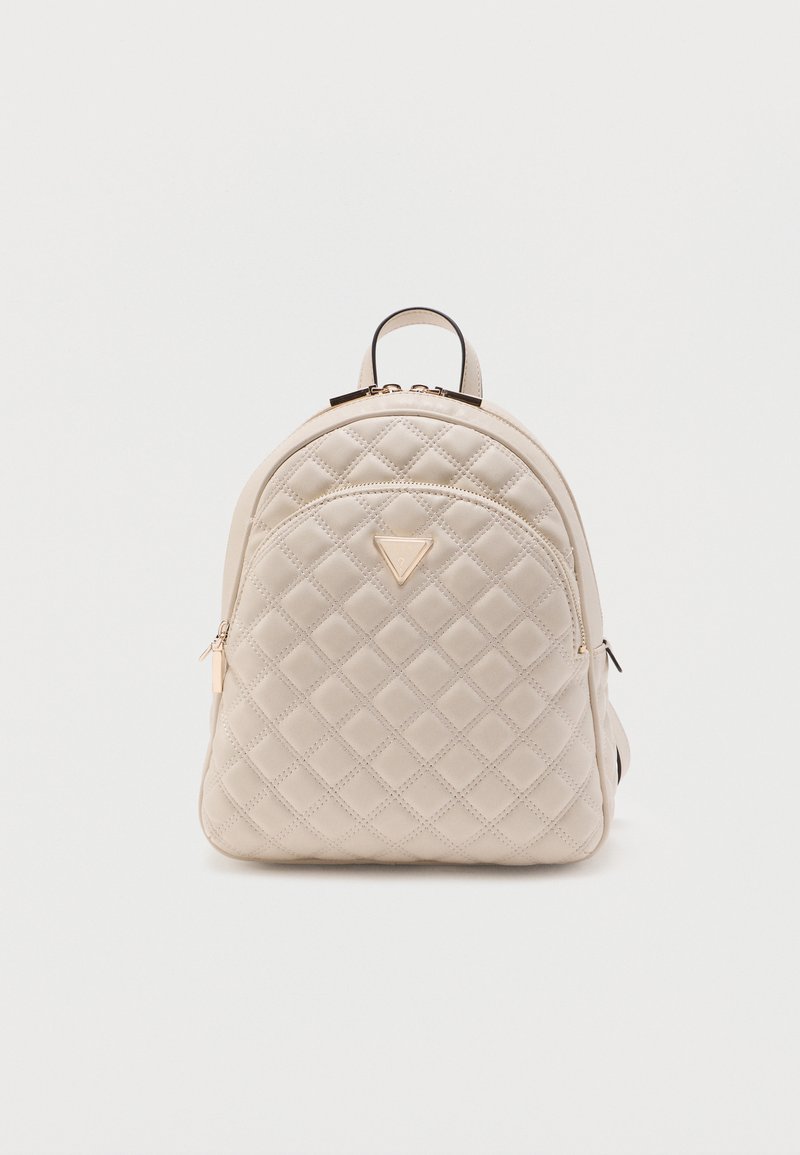 Sac à dos matelassé beige avec poche zippée à l'avant, logo triangulaire doré et poignée supérieure sur fond blanc uni.