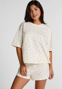 Crème katoenen loungewear-set met korte mouwen, ronde halslijn en zwarte stippen. Inclusief bijpassende shorts met een elastische tailleband.