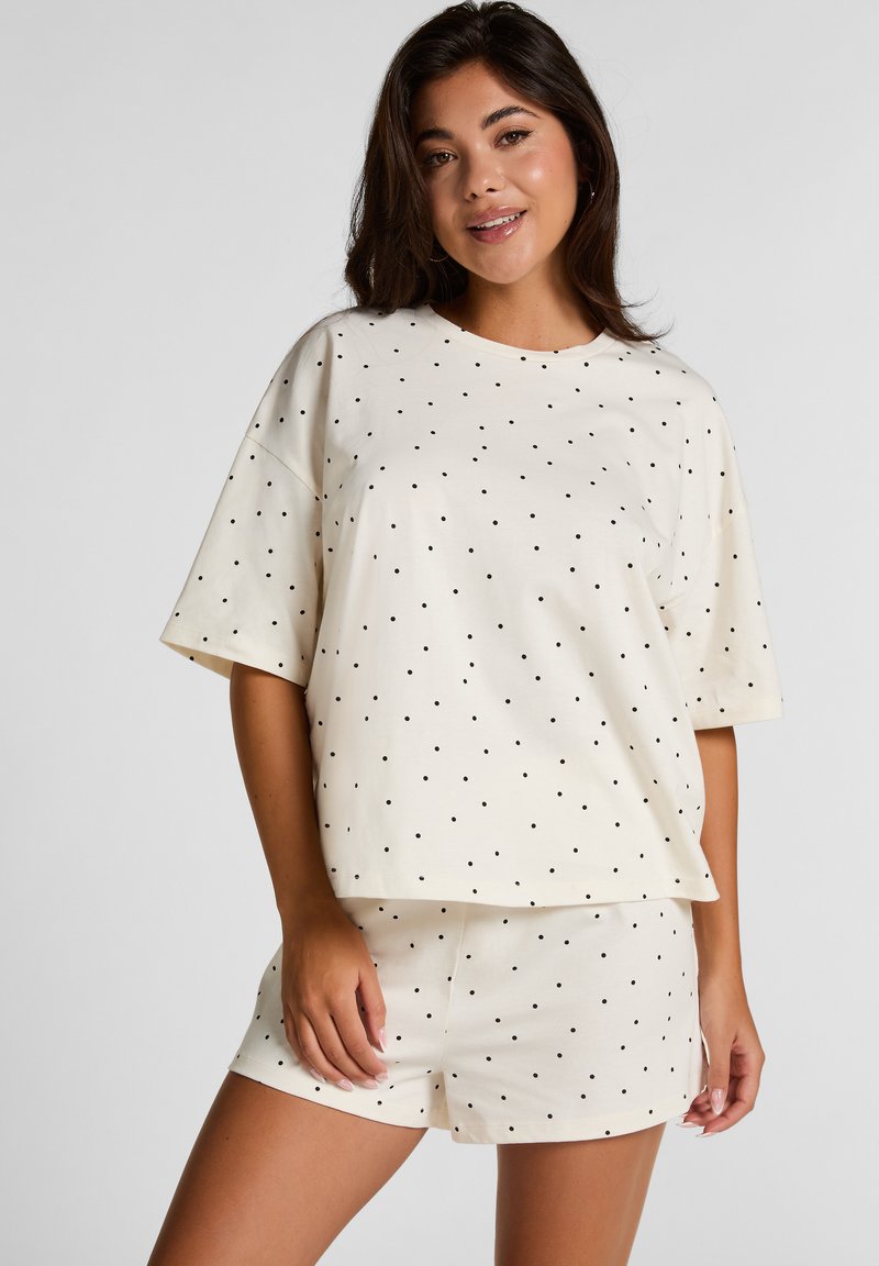 Crème katoenen loungewear-set met korte mouwen, ronde halslijn en zwarte stippen. Inclusief bijpassende shorts met een elastische tailleband.