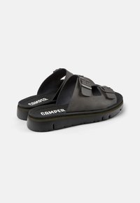 Sandal nero con due cinturini regolabili a fibbia, una soletta imbottita e una suola in gomma spessa con il nome del marchio "Camper."