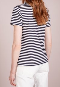 Marinblå och vitrandig T-shirt, korta ärmar, mjukt bomullstyg, avslappnad passform, rundad halsringning, bakre vy visar sömdetaljer och fast fåll.