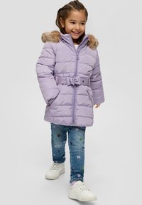 Jasnofioletowa kurtka puchowa z kapturem z sztucznego futra, paskiem w talii i zamkiem błyskawicznym z przodu. Połączona z dżinsami z haftem i białymi sneakersami.